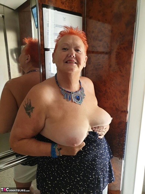 Fat nan with short red hair presses her big boobs and butt up against glass | Фото 1