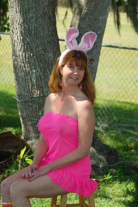 Older redhead Dee Delmar bares her tits and twat in yard wearing bunny ears