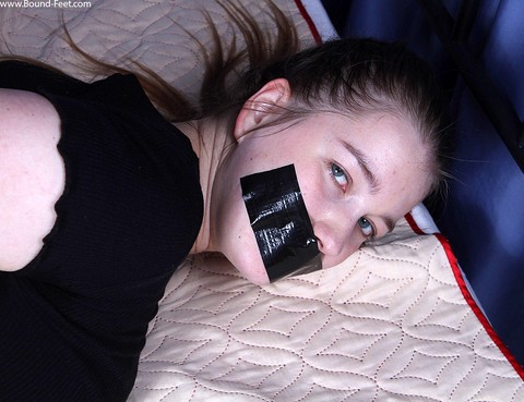 Clothed girl is silenced with duct tape while cuffed and hogtied on a bed | Фото 13