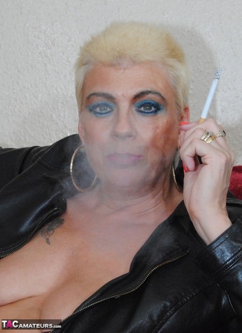 Mature woman with short blonde hair smokes while showing her boobs | Фото 1