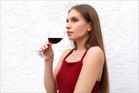 Beautiful girl removes a red dress over a glass of wine to pose in the nude | Фото 1