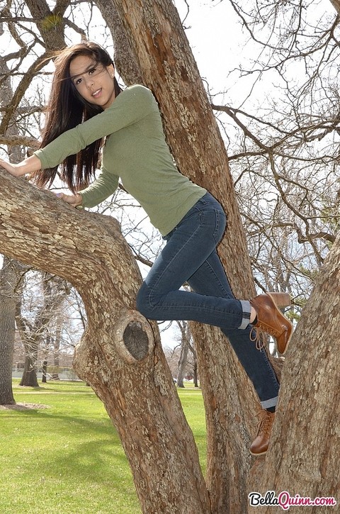 Latina chick Bella Quinn climbs a tree in the park wearing a sweater and jeans | Фото 9