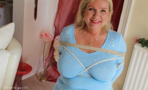 Older blonde is gagged and tied up in a variety of outfits inside her house | Фото 16