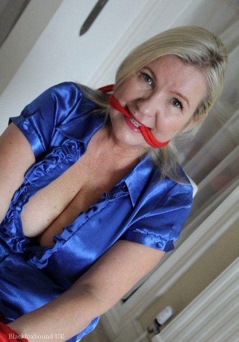 Older blonde is gagged and tied up in a variety of outfits inside her house | Фото 9