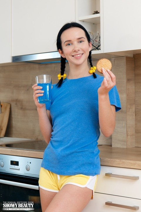 Young looking girl Natasha eats a cookie while getting naked in the kitchen | Фото 2