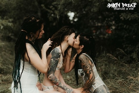 Three tattooed girls share lesbian kisses in long grass near a fir tree | Фото 10