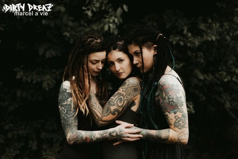 Three tattooed girls share lesbian kisses in long grass near a fir tree | Фото 11