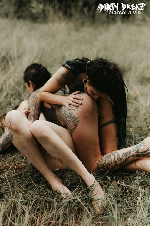 Three tattooed girls share lesbian kisses in long grass near a fir tree | Фото 5