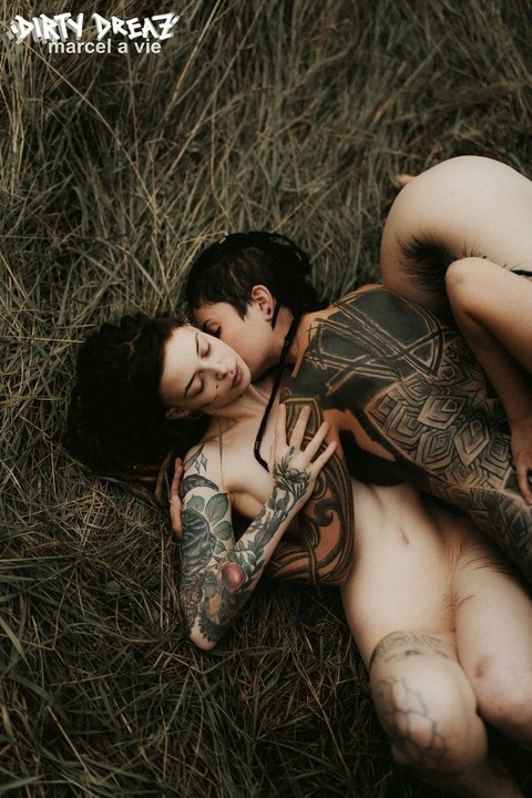 Three tattooed girls share lesbian kisses in long grass near a fir tree | Фото 8