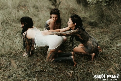 Three tattooed girls share lesbian kisses in long grass near a fir tree | Фото 9