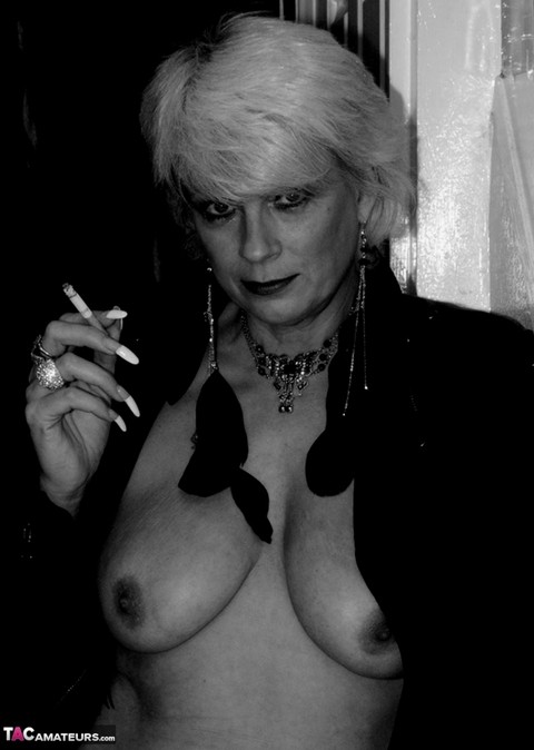 Older blonde lights a cigarette while showing her bare breasts and pussy | Фото 15