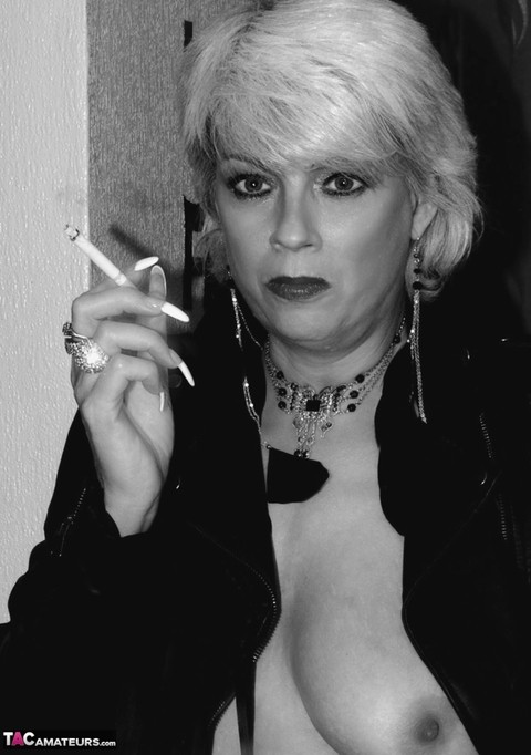 Older blonde lights a cigarette while showing her bare breasts and pussy | Фото 2