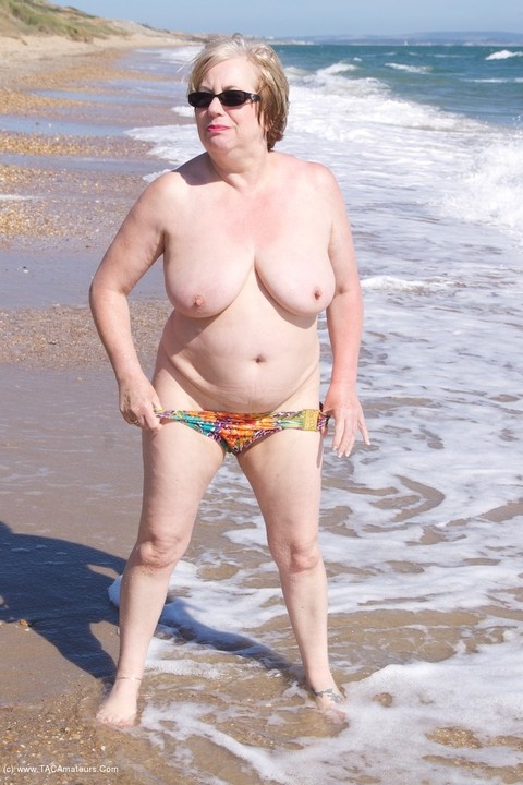 Mature UK woman Speedy Bee wears sunglasses while getting naked at the beach | Фото 16