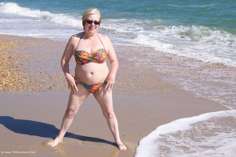 Mature UK woman Speedy Bee wears sunglasses while getting naked at the beach | Фото 2