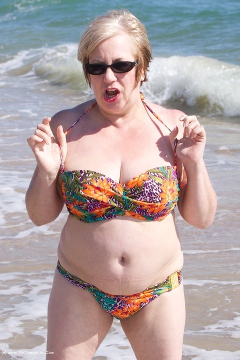 Mature UK woman Speedy Bee wears sunglasses while getting naked at the beach | Фото 4