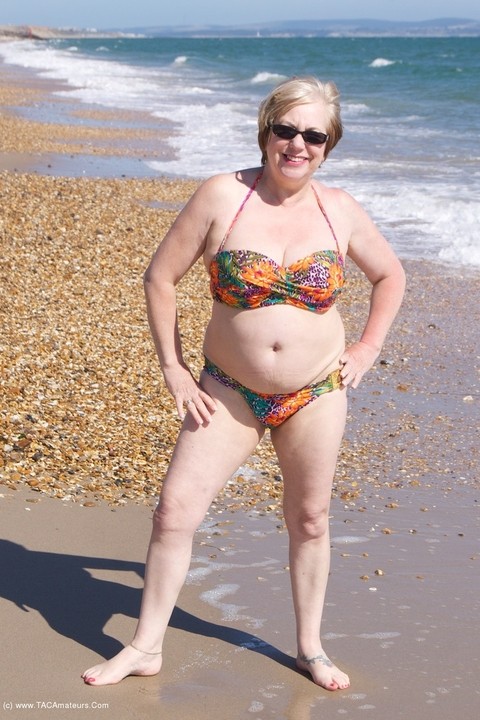 Mature UK woman Speedy Bee wears sunglasses while getting naked at the beach | Фото 6