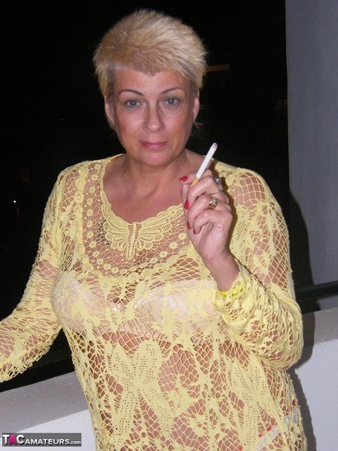 Middle-aged blonde Dimonty smokes while getting completely naked