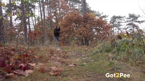 Clothed girl pulls down her pants to take a piss on a path thru the woods | Фото 1