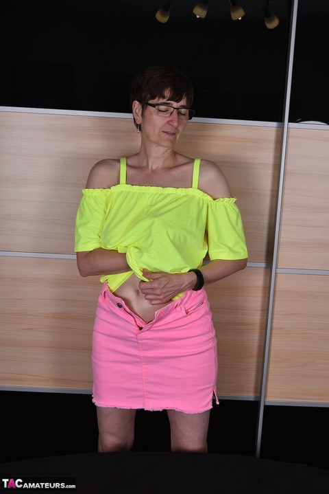 Mature woman undoes the snap and zipper on a pink miniskirt during SFW action | Фото 12