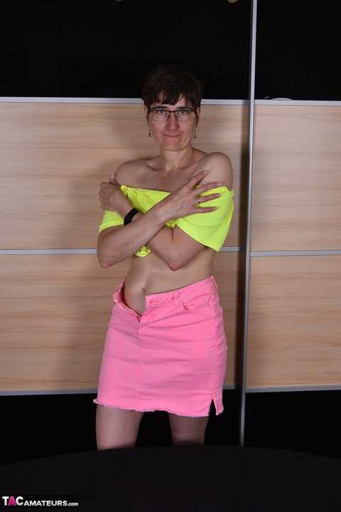 Mature woman undoes the snap and zipper on a pink miniskirt during SFW action | Фото 16