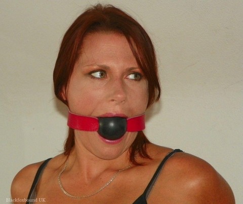 Natural redhead restrained on a bed while gagged in her clothes and heels