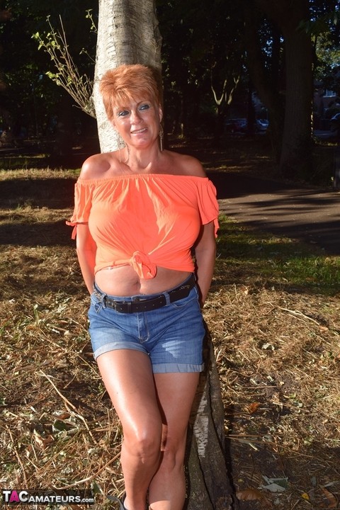 Mature redhead Dimonty shows her tits on a bench in a country field | Фото 11