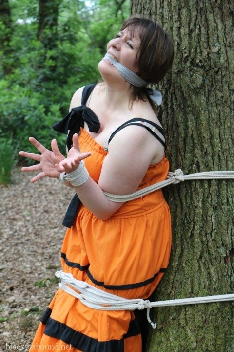 Fat female is gagged and tied to a tree in the woods with her clothes on | Фото 13