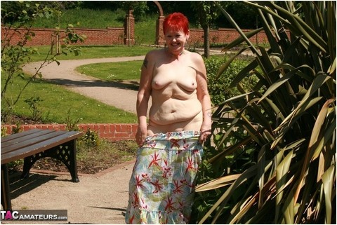 Older redhead Valgasmic Exposed gets totally naked in a public park | Фото 1