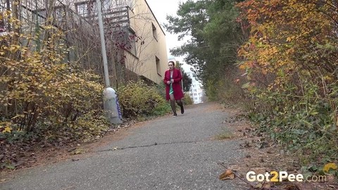 Caucasian female Lora takes a piss while walking on a pathway in the city | Фото 1