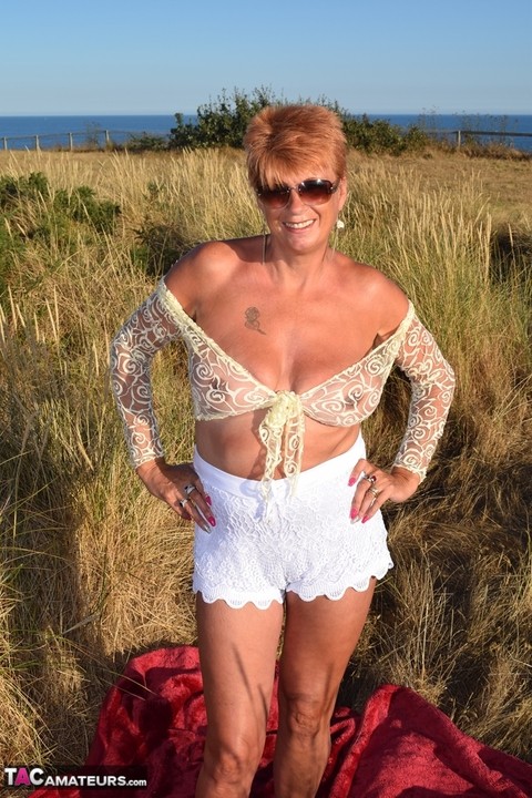 Fit older lady Dimonty exposes big naturals on a blanket overlooking the ocean | Фото 13