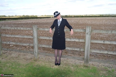 Mature policewoman Barby Slut removes her uniform against a fence at a farm | Фото 1