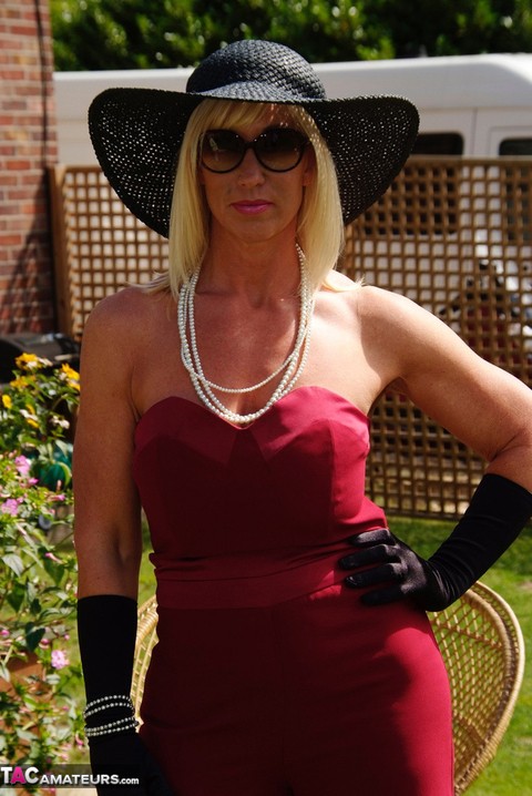 Blonde MILF displays her large tits in a big hat and gloves while in a yard | Фото 1