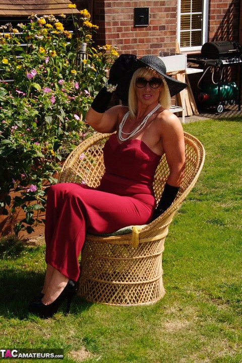 Blonde MILF displays her large tits in a big hat and gloves while in a yard | Фото 6