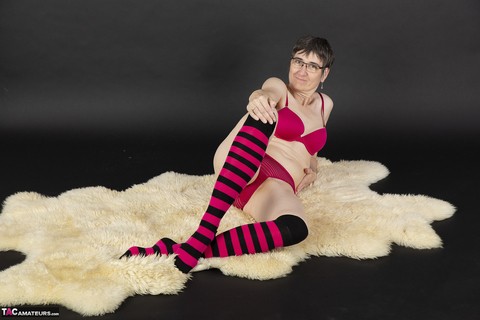 Mature woman removes her bra and underwear to pose nude in striped knee socks | Фото 2