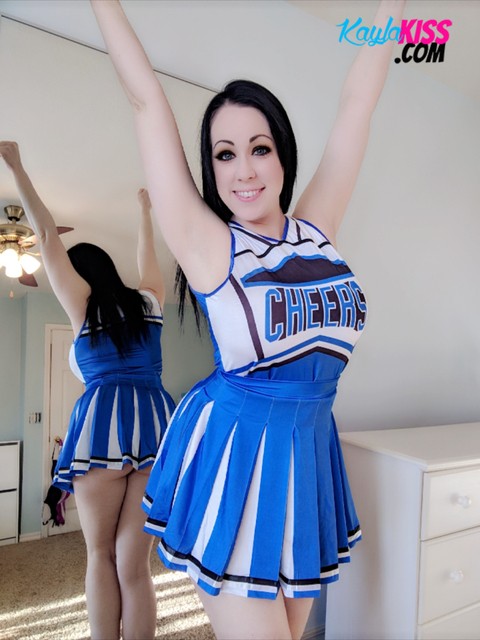 Dark-haired cheerleader Kayla Kiss uncovers her big natural tits in OTK socks | Фото 1