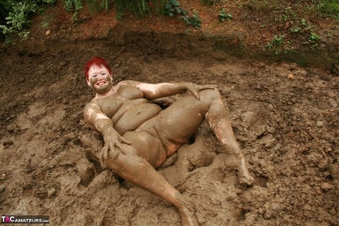 Older redhead Valgasmic Exposed rolls around in a mud pit while totally naked | Фото 17