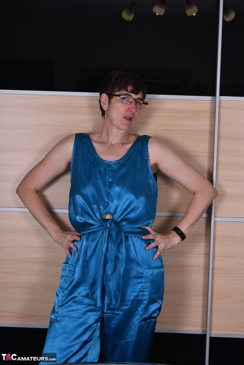 Amateur woman models satin evening wear on a bed with her glasses on | Фото 1