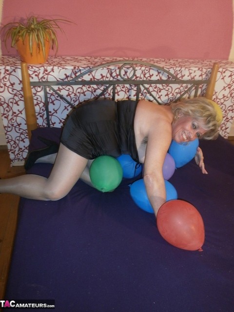 Hot granny Caro in shiny sheer pantyhose & heels crushing balloons on her bed | Фото 12