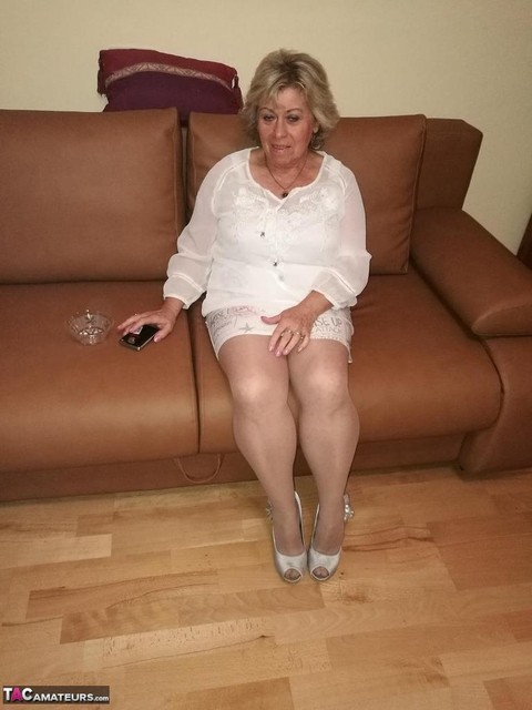 Mature lady exposes her large tits while having a smoke in pantyhose | Фото 1