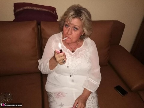 Mature lady exposes her large tits while having a smoke in pantyhose | Фото 3