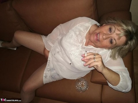 Mature lady exposes her large tits while having a smoke in pantyhose | Фото 9