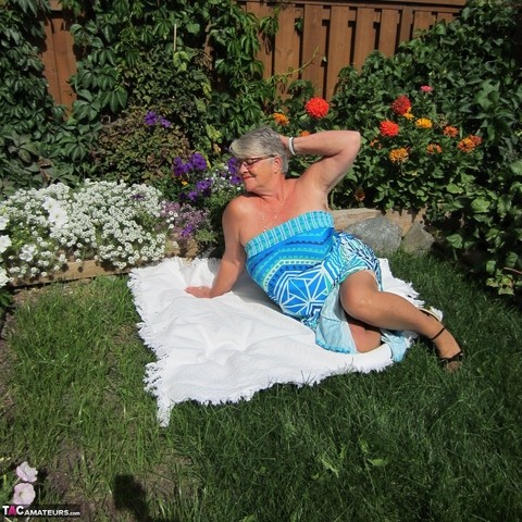 Fat nan Girdle Goddess strips to sheer pantyhose on a blanket by a flower bed | Фото 1