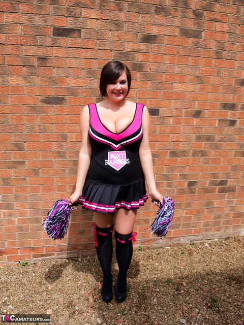 Chubby cheerleader Roxy uncovers her large tits against a brick wall | Фото 1