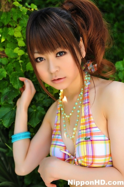 Tiny Asian girl wears her hair in a ponytail while modeling a bikini by a pool