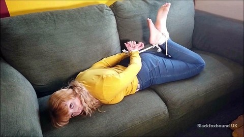 Barefoot white girl is hogtied on a sofa while ball gagged in her clothing | Фото 7