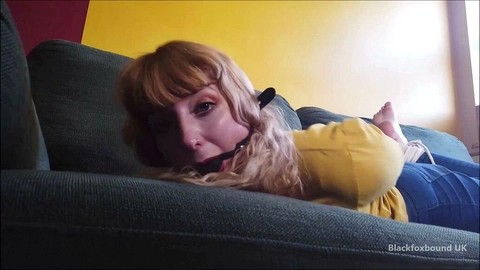 Barefoot white girl is hogtied on a sofa while ball gagged in her clothing | Фото 9