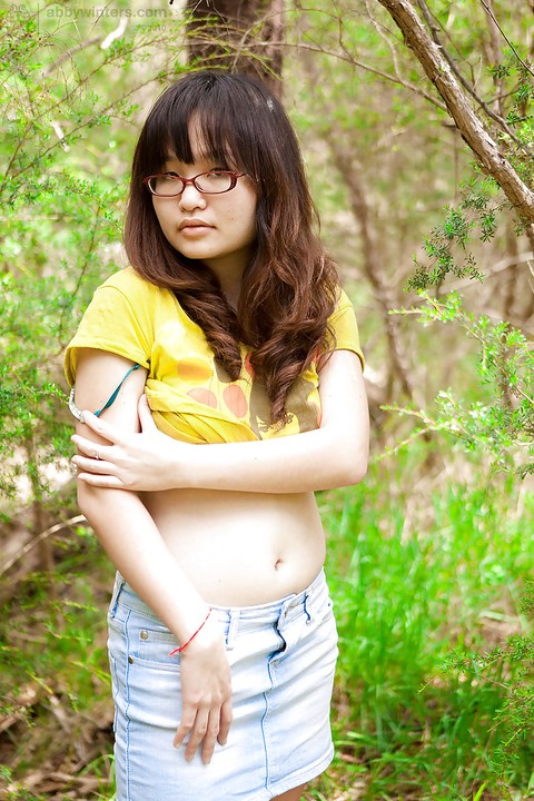 Petite Asian girl in glasses bares hairy vagina outdoors after slow strip | Фото 3