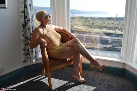 Big titted older woman Barby Slut showcases her bald twat in front of a window | Фото 1