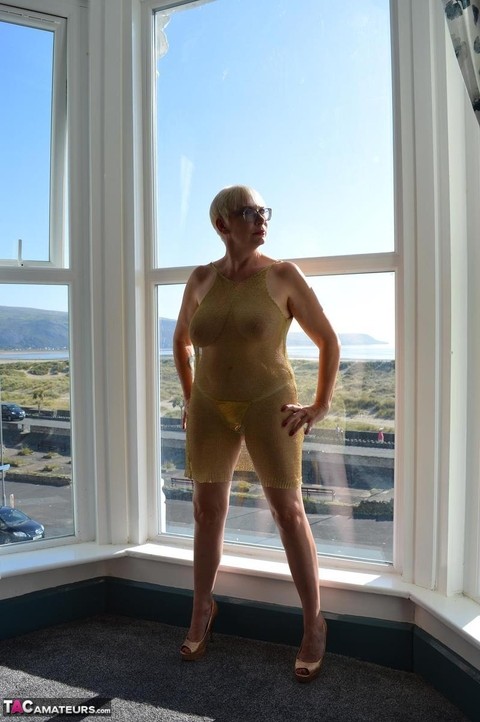 Big titted older woman Barby Slut showcases her bald twat in front of a window | Фото 4