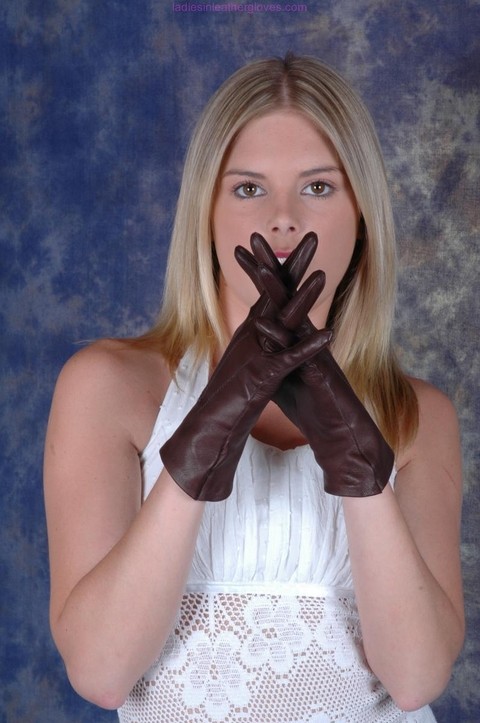 Blonde female pulls on brown leather gloves while wearing a white dress | Фото 12